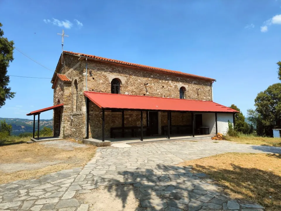 Η πέτρινη εκκλησία των Ταξιαρχών με την κόκκινη στέγη και το πλακόστρωτο προαύλιο