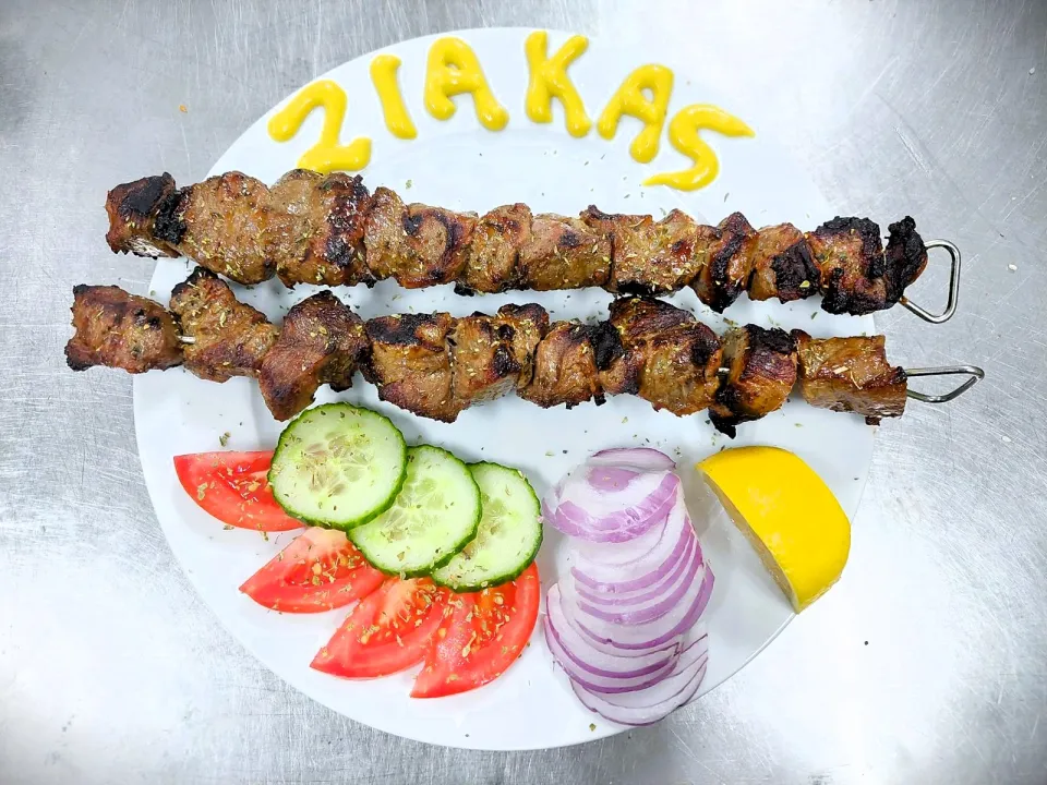 Πιάτο με καλαμάκια, ντομάτα, αγγούρι, κρεμμύδι και λεμόνι, με τη λέξη «Ziakas» γραμμένη στο πιάτο