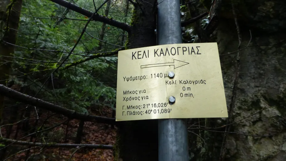 Πινακίδα «Κελί Καλογριάς» στο δάσος, με το υψόμετρο και τις συντεταγμένες